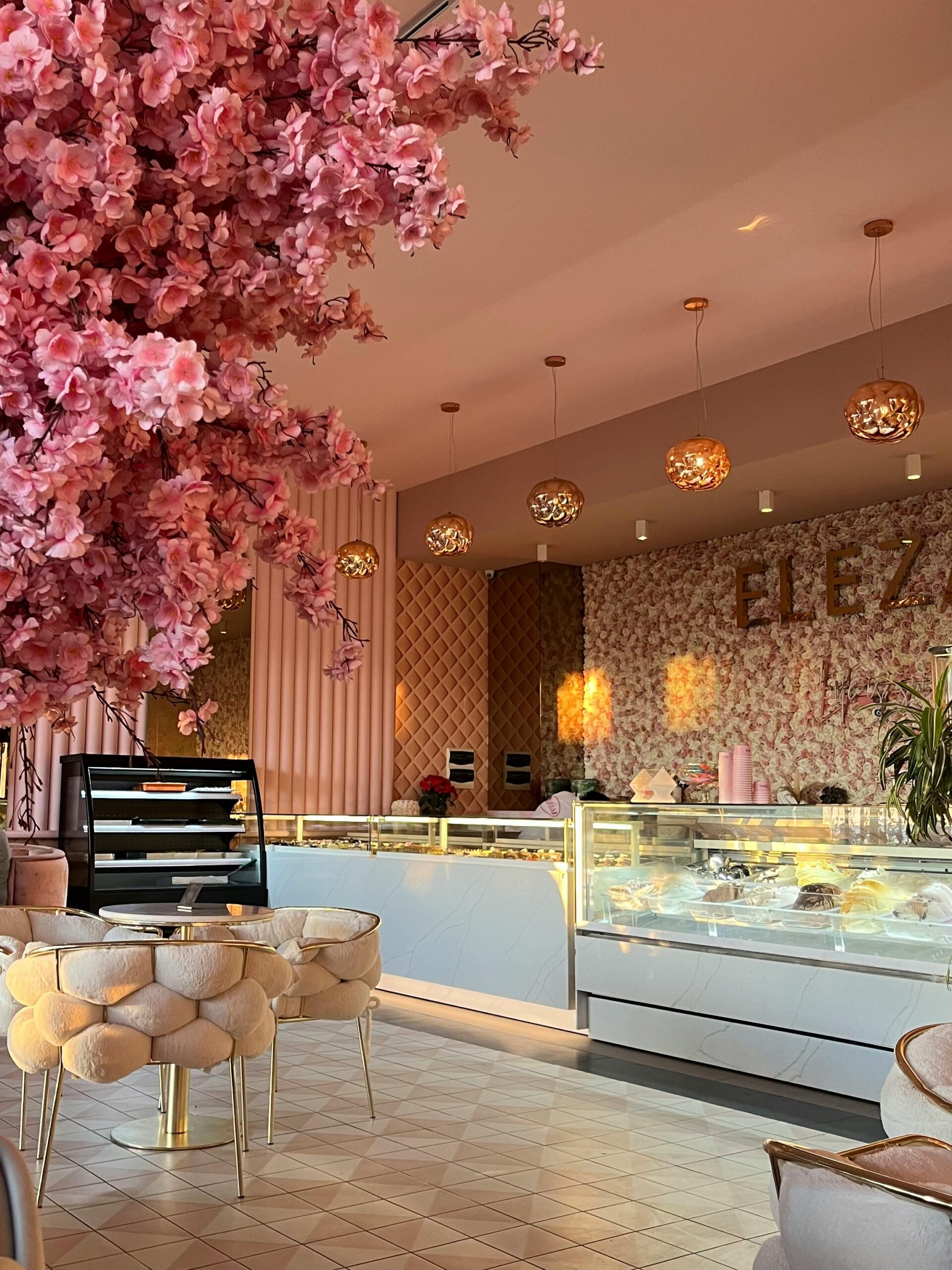 A cozy pink cafe featuring elegant modern decor and floral arrangements.